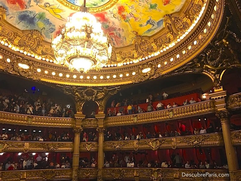 Opera Garnier's auditorium, a part of the roof is visible as well as the giant chandelier and the box seats where the public is getting ready to go out