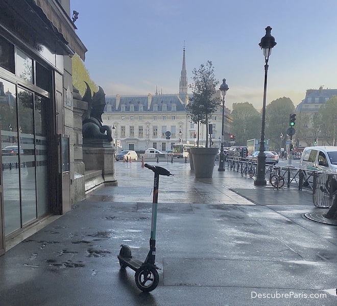 En primer plano se ve un monopatín y en el fondo se ve el edificio de la conserjería de paris