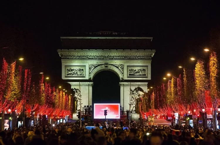 se ven los campos elíseos iluminados con luces rojas y al fondo el arco del triunfo